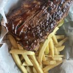 Bbq ribs and fries in a paper bag.